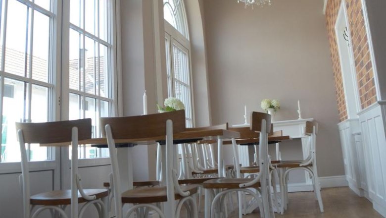 Kammer und Koppel, © Julia Pfeiffer / Fam. Engelbrecht Eleganter Raum mit hohen Fenstern, Kronleuchtern und Holzmöbeln.