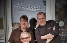 Norbert Hacker und sein Team, © Restaurant Hacker's Drei Personen vor dem Eingang von Hacker's Restaurant & Weinbar.