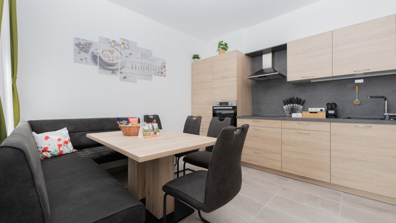 Gemeinschaftsküche, © Schönfelderhof Moderne Küche mit Holzmöbeln, Esstisch, Eckbank und Stühlen.