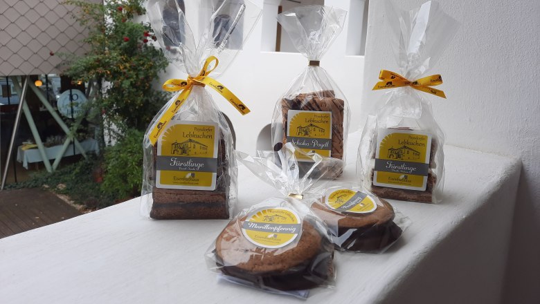 Lebkuchen, © Eisenhuthaus Abgepackter Lebkuchen im Vordergrund, weißer Arkadenhof im Hintergrund.