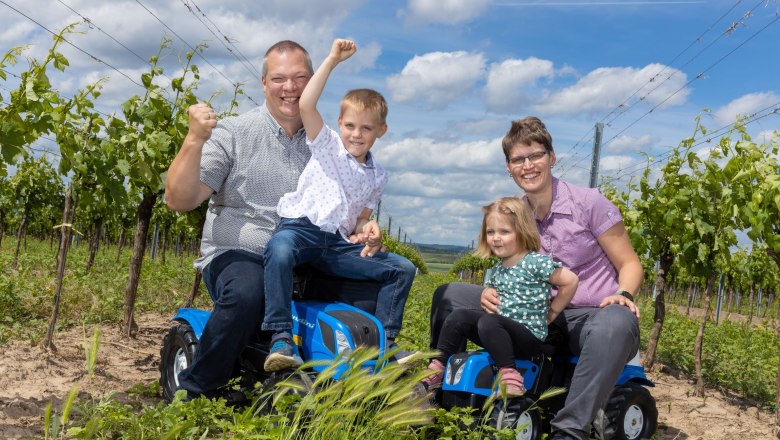 Laurer family, © Helge Woell Family sitting on toy tractors in the vineyard.