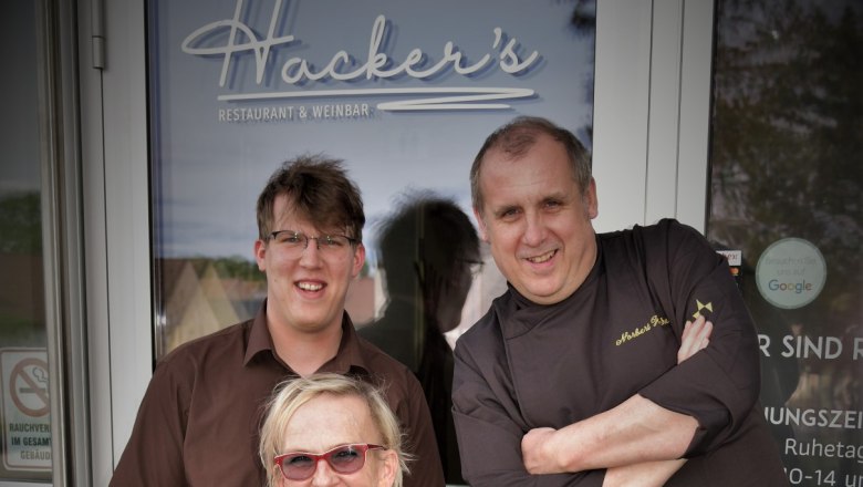 Norbert Hacker and his team, © Restaurant Hacker's Three people in front of the entrance to Hacker's Restaurant & Wine Bar.