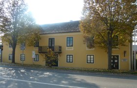 Erzherzog Carl Haus und Napoleonmuseum Deutsch-Wagram, © Erzherzog Carl Haus Gelbes Gebäude mit Balkon und Bäumen davor, Erzherzog Carl Haus und Napoleonmuseum in Deutsch-Wagram.