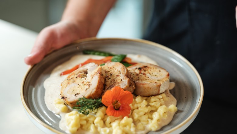 Kulinarik im freilich, © Michael Reidinger Ein Teller mit gefülltem Fleisch, Spätzle, Gemüse und einer Blume als Garnitur.