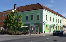 Weinhotel Rieder, © Familie Rieder Grünes Gebäude mit Hotel- und Café-Schildern an einer Straßenecke.