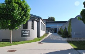 MAMUZ Museum Mistelbach, © MAMUZ Eingang des MAMUZ Museums Mistelbach mit Wegweiser und Bäumen.