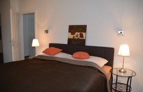 Ferienwohnung, © Familie Herrmann Schlafzimmer mit Doppelbett, zwei Nachttischlampen und einem Gemälde an der Wand.