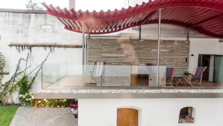 Klinger's Gästehaus, © Astrid Bartl Terrasse mit roten Dach und Liegestühlen in einem Gästehaus.