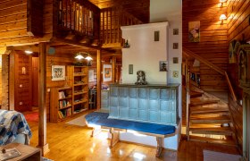 Gemütlichkeit rund um den Kachelofen, © Imre Antal Gemütliches Wohnzimmer mit Kachelofen, Holzwänden und Treppe.