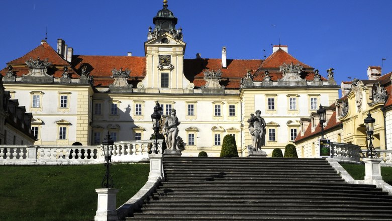 Schloss Valtice, © Weinviertel Tourismus / Mandl Frontansicht des Schlosses Valtice mit Treppen und Statuen im Vordergrund.