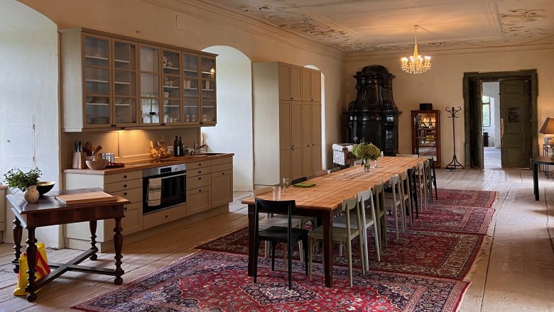 Speisesaal, © Schloss Haggenberg Eleganter Speisesaal mit langem Holztisch, Kronleuchtern und antikem Ofen.