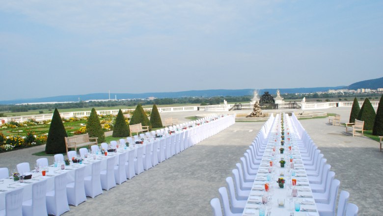 Tafeln im Weinviertel, © Weinviertel Tourismus GmbH Langer, festlich gedeckter Tisch im Freien mit Blick auf einen Garten und eine Statue.