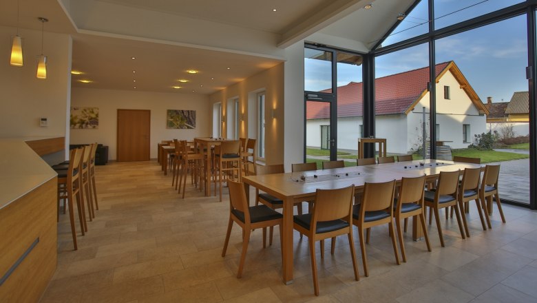 The Vino.Taste, © Helge Woell Interior view of a modern tasting room with wooden furniture and large windows.