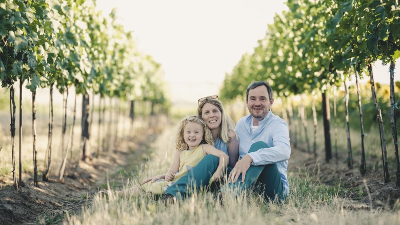 Familie Weinwurm, © Michael Reidinger Familie sitzt zwischen Weinreben in einem Weinberg.