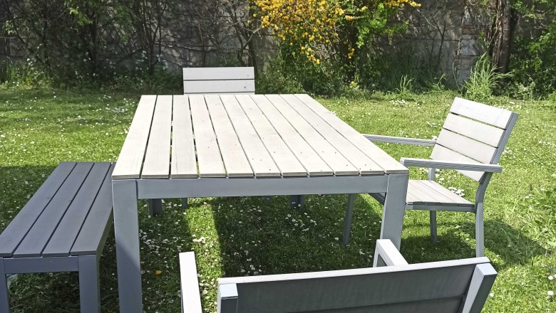 Sitzmöglichkeiten im Außenbereich, © Multimedia Lauda Gartenmöbel-Set mit Tisch, Stühlen und Bank auf einer Wiese.