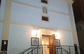 Opus Außenansicht, © Nicolas Engel Eingang eines Gebäudes mit Treppe und geöffneten Türen, beleuchtet bei Nacht.