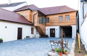 Gaestehaus Teufelsbauer, © Melanie Rutschek Innenhof eines Gästehauses mit Holzelementen und gepflastertem Boden.