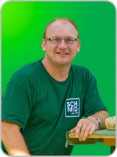Winzer, © Rainer Schmid Person in grünem T-Shirt mit Logo, lächelnd vor grünem Hintergrund.