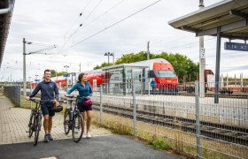 Bahnhof, © Weinviertel Tourismus GmbH / POV / Robert Herbst Zwei Personen mit Fahrrädern am Bahnhof, im Hintergrund ein ÖBB-Zug.