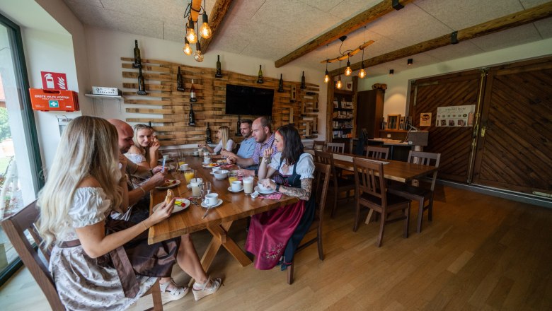 Winery Küssler, © Winzerhof Küssler Group of people in traditional dress sitting at a table in a rustic room.