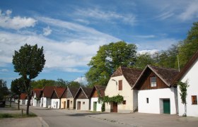 Kellergasse Jetzelsdorf, © Andreas Sedlmayer Reihe von traditionellen Weinkellern in Jetzelsdorf unter blauem Himmel.