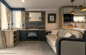 Wohnraum, © Leopold Pluschkowitz Gemütliches Wohnzimmer mit Sofa, Kamin, Spiegel und Küche.