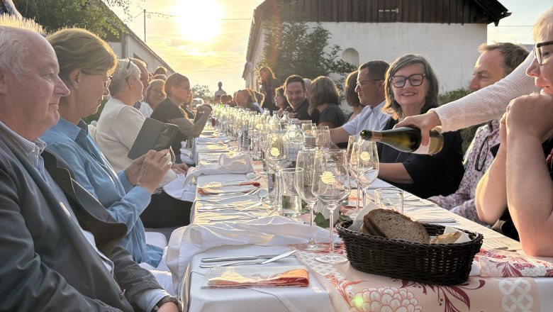 Tafeln im Weinviertel, © Weinviertel Tourismus GmbH Menschen sitzen an einer langen Tafel im Freien bei Sonnenuntergang.