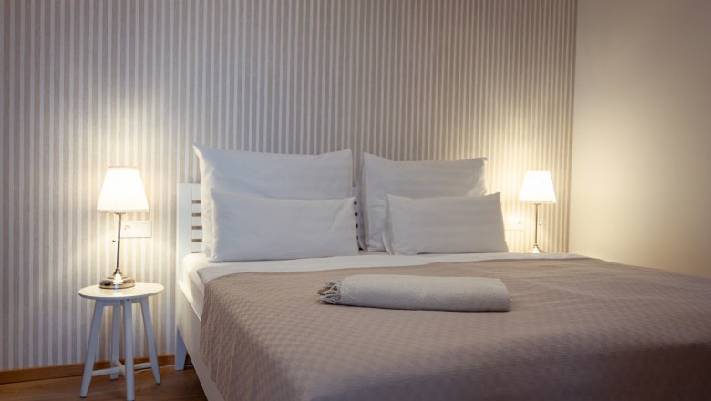 Hausgnost Apartments, © Niederösterreich Werbung / Maximilian Pawlikowsky Modernes Schlafzimmer mit Doppelbett, Nachttischen und Lampen.