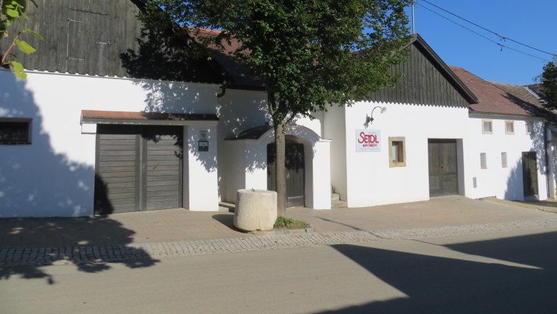 Keller, © Fam. Seidl Weißes Gebäude mit Holzverkleidung und Schild 'Seidl am Dach'.