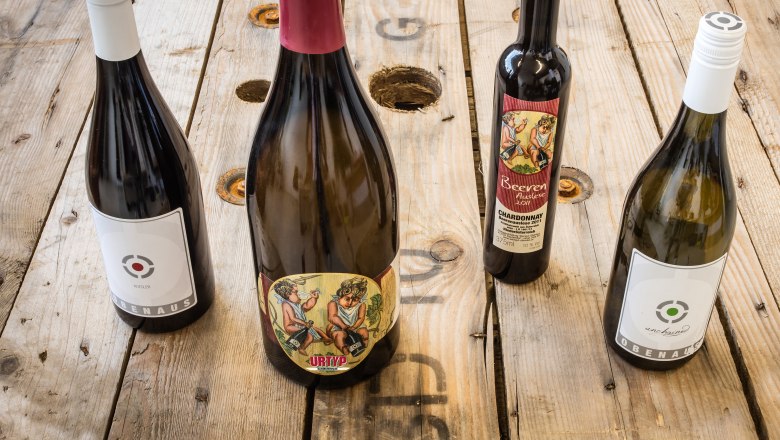 Weinspezialitäten, © Martin Obenaus Vier Weinflaschen auf einem Holztisch.