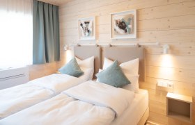 Doppelzimmer, © freilich / IsaBella Fritsche Gemütliches Doppelzimmer mit zwei Einzelbetten, Holzwänden und moderner Dekoration.