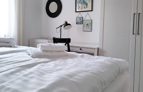 Zimmer zum Wohlfühlen, © Quartier35 Helles Schlafzimmer mit Doppelbett, Schreibtisch und Wanddekoration.