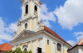 Augustiner Kirche, © Stadtgemeinde-Korneuburg Barocke Kirche mit Turm und Uhr vor blauem Himmel.