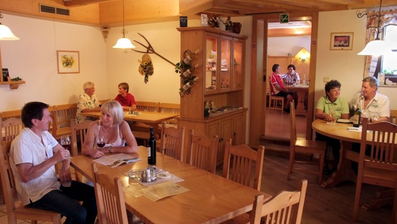 Heurigenlokal, © Seymannfilm Innenansicht eines gemütlichen Restaurants mit mehreren Gästen an Holztischen.