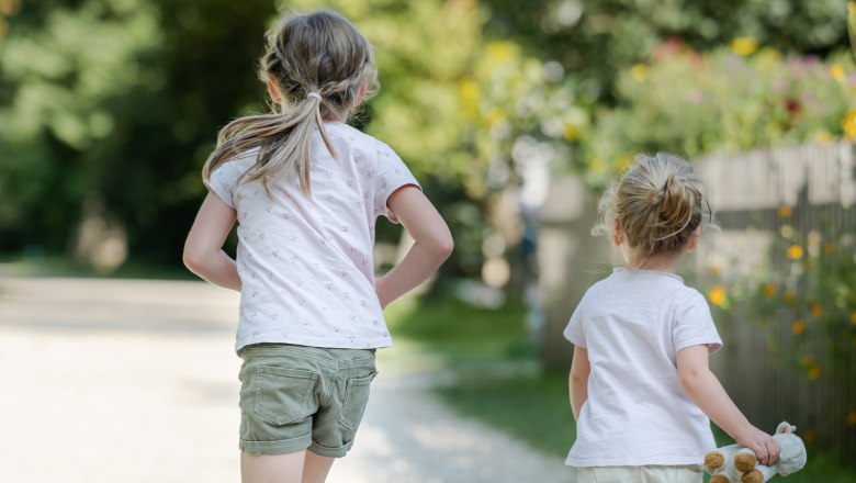 Children at play, © Niederösterreich Werbung / Claudia Schlager Two children run along a gravel path in a park, surrounded by trees and flowers.