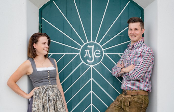 Stephanie and Lukas, © Christopher Anker A man and a woman in traditional dress in front of a green door with a geometric pattern.