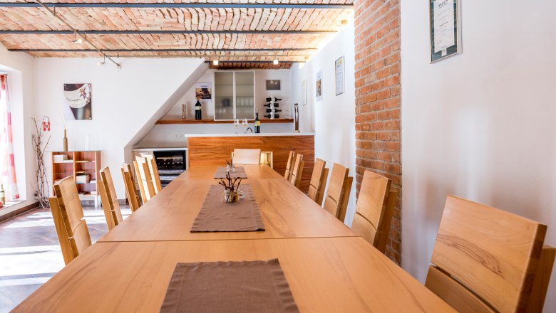 Verkostungsraum, © Reinhard Podolsky Verkostungsraum mit langem Holztisch und Stühlen, Ziegeldecke und Weinregal.
