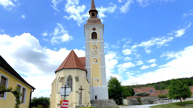 Schiefer Turm von Waitzendorf, © Weinstraße Weinviertel Kirche mit schiefem Turm in Waitzendorf, umgeben von blauen Himmel und Wolken.