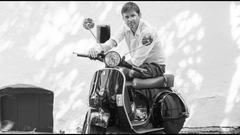 Wolfgang Seher, © Weingut Seher Person auf einer Vespa vor einer weißen Wand.