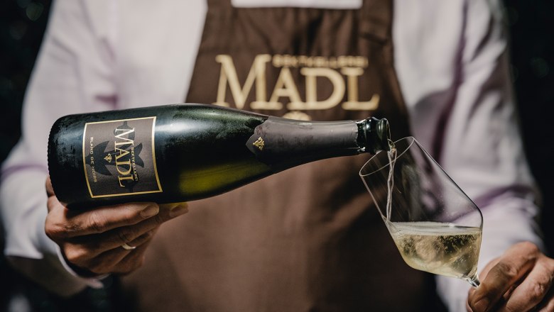 Christian Madl, © Madl / Michael Reidinger Person schenkt Sekt aus einer Madl-Flasche in ein Glas ein.
