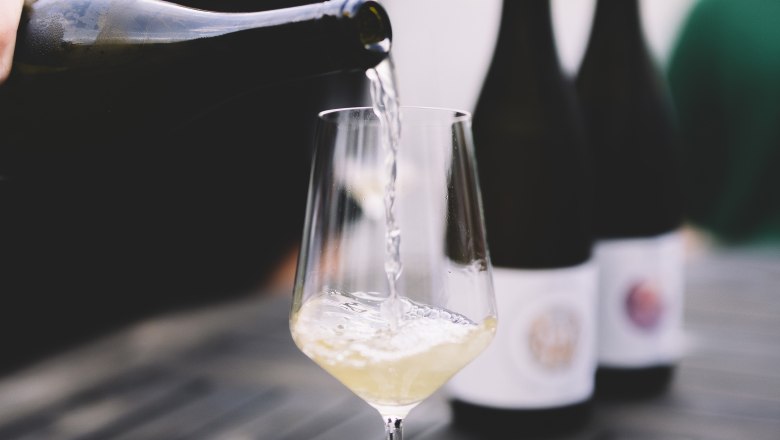 Pouring wine, © Niederösterreich Werbung / Mara Hohla White wine is poured into a glass on a table.