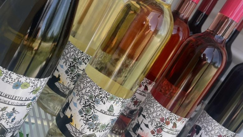 Radlerrast, © Weingut Grillmeier-Ladentrog Weinflaschen in einem Kühlschrank mit bunten Etiketten.