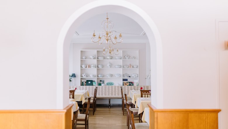 Kreative Küche in traditionellem Wirtshausambiente, © Niederösterreich Werbung/Sophie Menegaldo Innenansicht eines traditionellen Wirtshauses mit gedeckten Tischen und einem Kronleuchter.