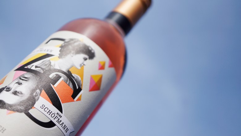 Wine, © Zuschmann-Schöfmann Close-up of a wine bottle with an artistic label against a blue sky.