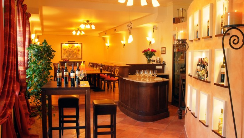 Verkostungsraum, © Seymann Ein eleganter Verkostungsraum mit Weinflaschen, Gläsern und stilvoller Beleuchtung.