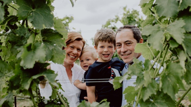 Familie Hofmeister, © Weingut Hofmeister Eine lächelnde Familie steht zwischen Weinreben in einem Weinberg.