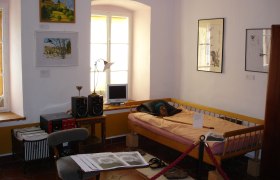 Gottfried von Einem Museum, © Stadtgemeinde Maissau Innenansicht eines Museumszimmers mit Bett, Bildern an der Wand und einem kleinen Schreibtisch mit Computer.
