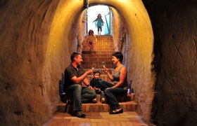 Euregio Vinothek, Gesunder Keller, © Seymann Familie sitzt in einem Weinkeller auf Treppen und trinkt Wein.