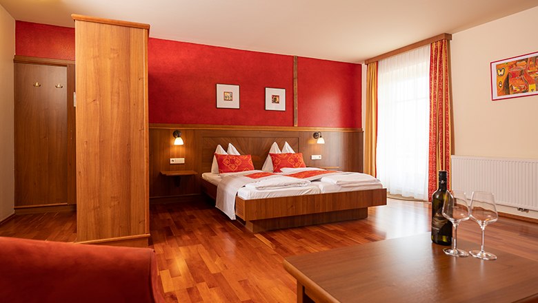 Doppelzimmer Hotel Neustifter, © Michael Reidinger Gemütliches Hotelzimmer mit Doppelbett, Holzmöbeln und roten Akzenten.