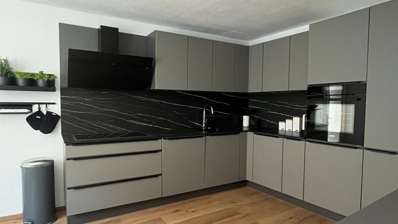 Kitchen unit, © Jochen Maurer Modern gray kitchen unit with black worktops and wooden floor.